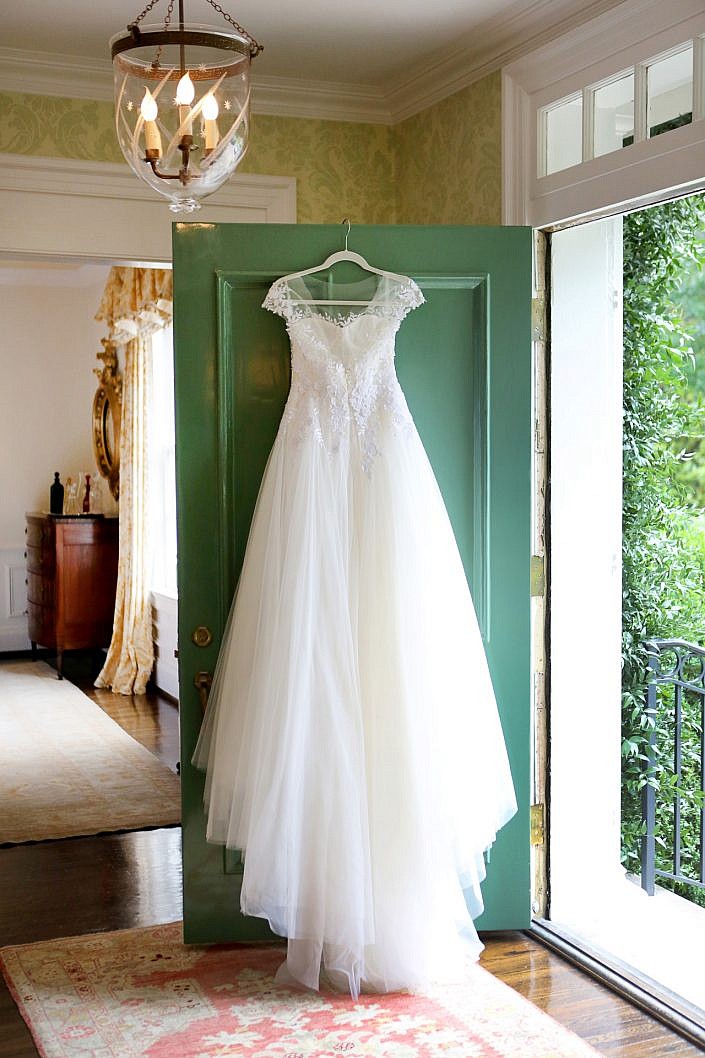 Mira Zwillinger couture wedding gown hanging on a green door