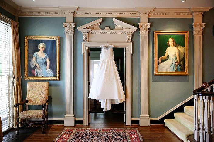 wedding gown hangs among family portraits