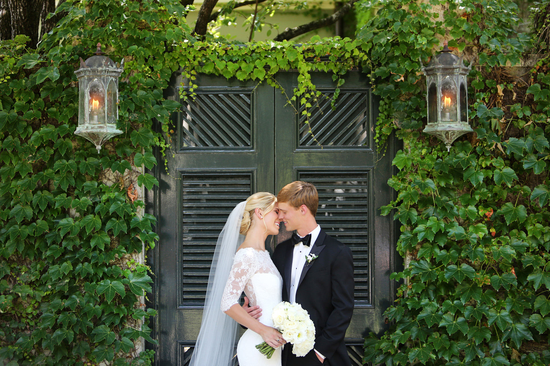 bride and groom kiss at garden gate covered with ivy